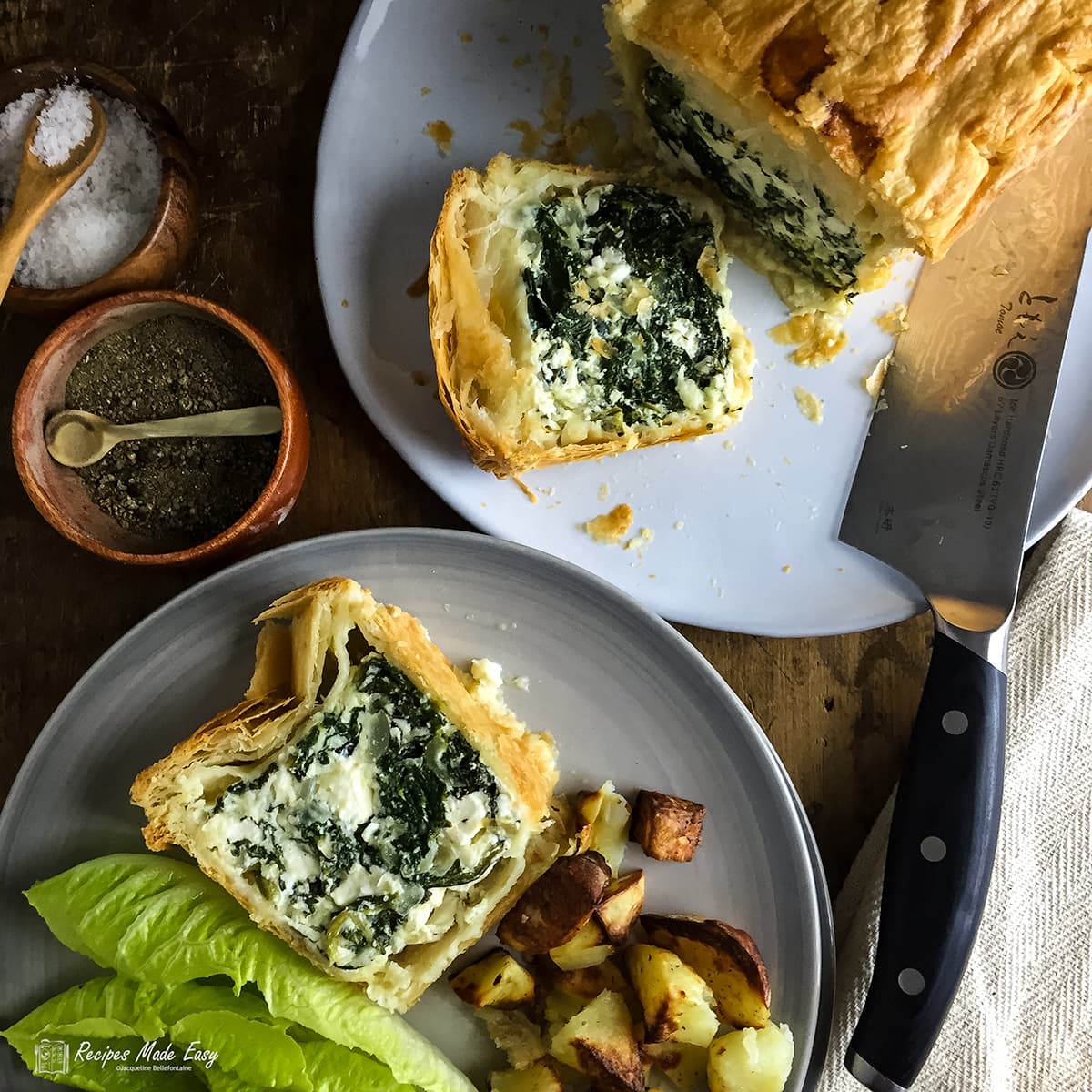 Two plates one with with spinach, ricotta and feta pie and a slice laying down the other with a slice served with lettuce and potatoes