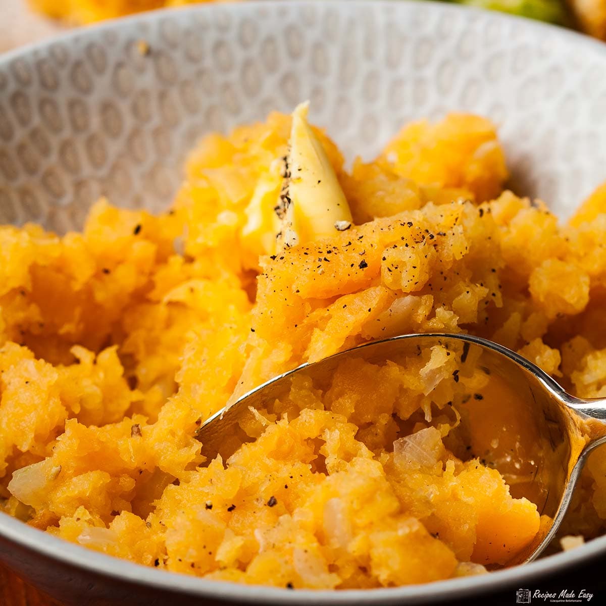 closeup of mashed swede in serving bowl, with spoon.