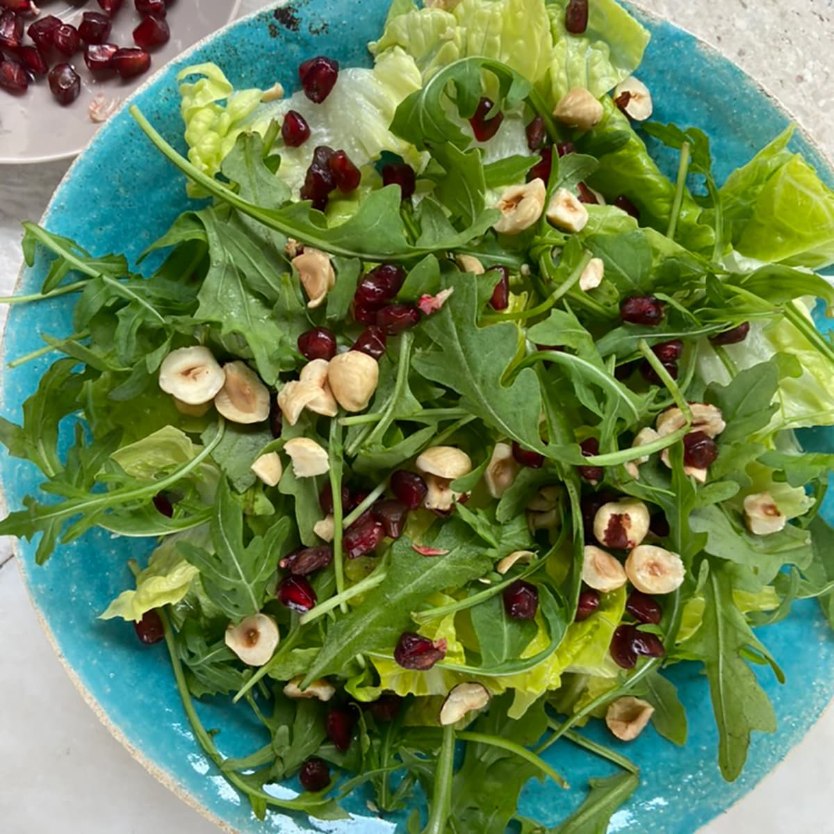 plate of green salad with hazelnuts and cranberries scattered over leaves